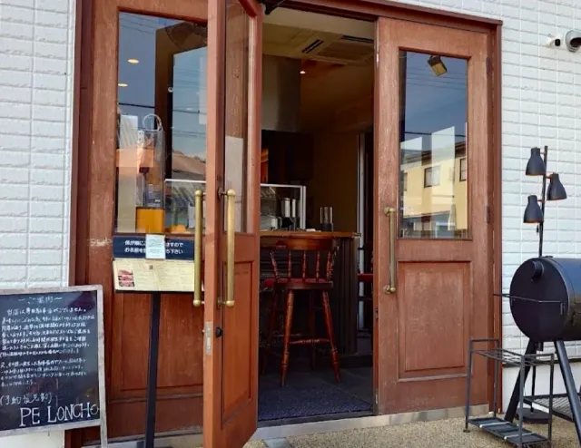 Open wooden double doors onto a small space with stools, a chalkboard and a smoker outside