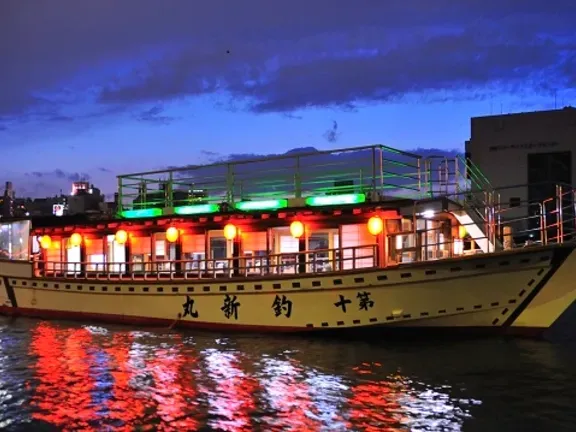 A traditional river boat with red lanterns and a blue sky after sunset