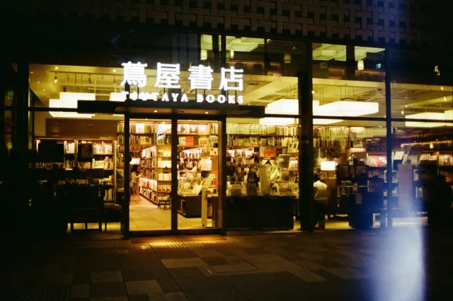 A bookshop lit in the evening, shelves visible through glass
