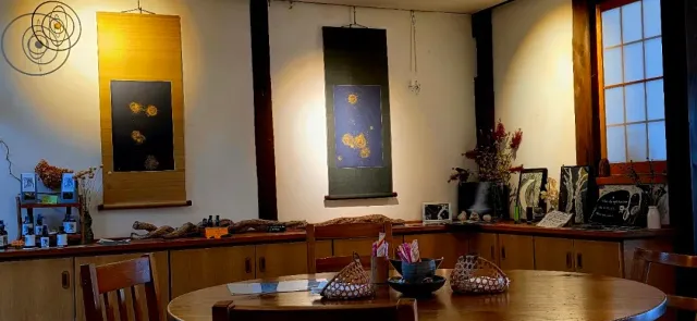 A room with two hanging painted scrolls, a round table and low wooden cabinets