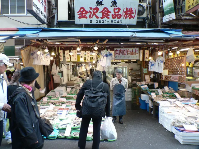 Shoppers at packed food stalls under a market canopy
