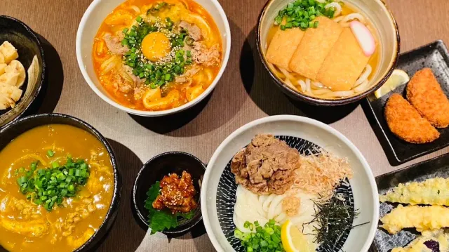 A view from above of noodle bowls in different broths, beside tempura and fried snacks