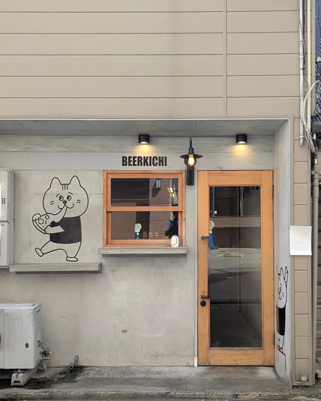 A small frontage with a glazed wooden door, a window and a cartoon cat painted on the wall