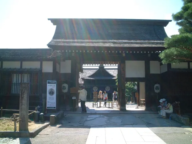A dark wooden gate and paved courtyard of a historic government compound
