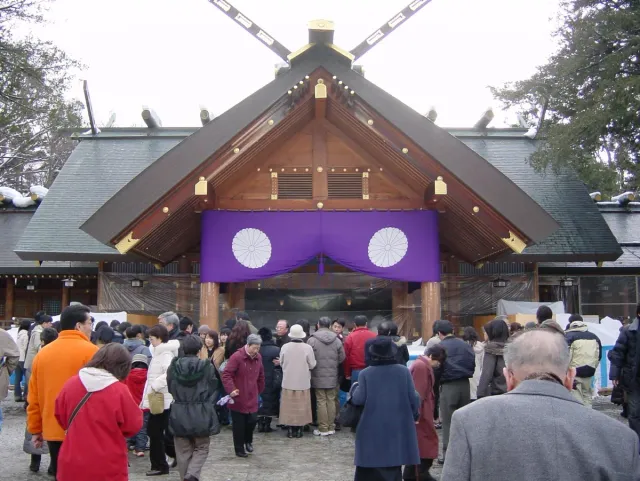 A crowd of worshippers in front of a shrine hall with a purple curtain