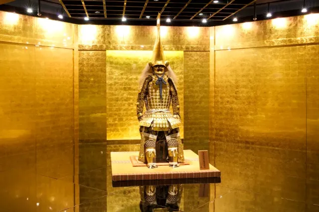 A room with gold covered walls, a samurai armor displayed on a low platform in the center