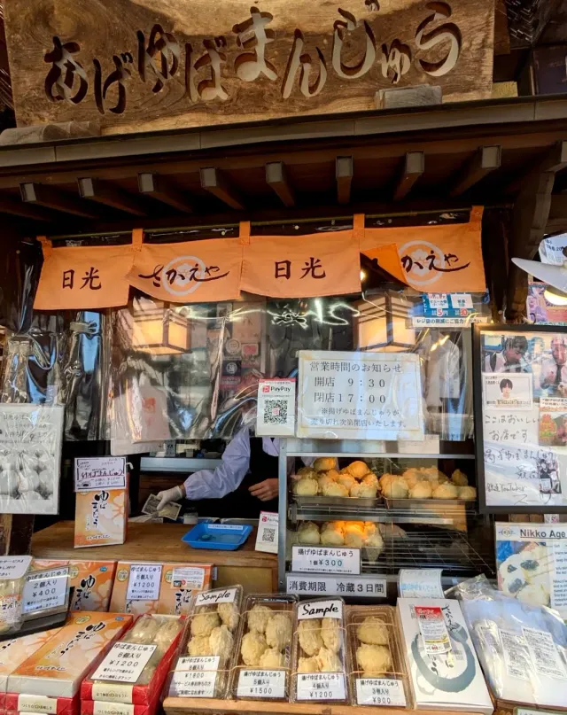 A stall with a carved wooden sign, orange curtains and a display case holding fried dough balls