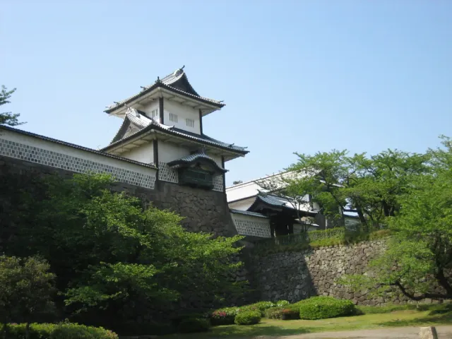 A castle gate with white walls and dark tiled roofs above a stone rampart