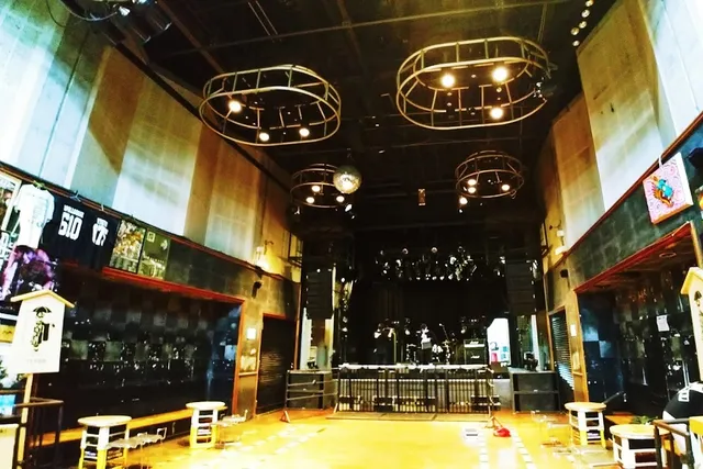 A concert hall with a stage at the far end, a high ceiling and hanging round lamps