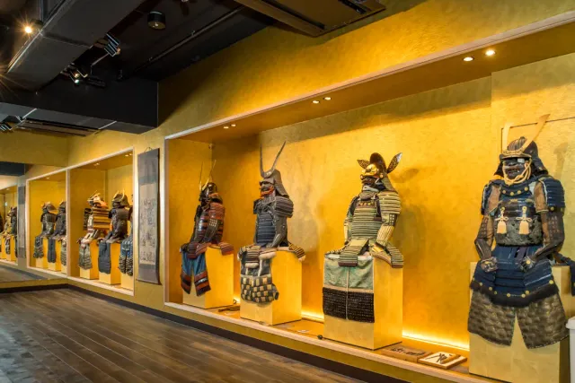Ancient battle armours in lit alcoves on a yellow wall along a corridor