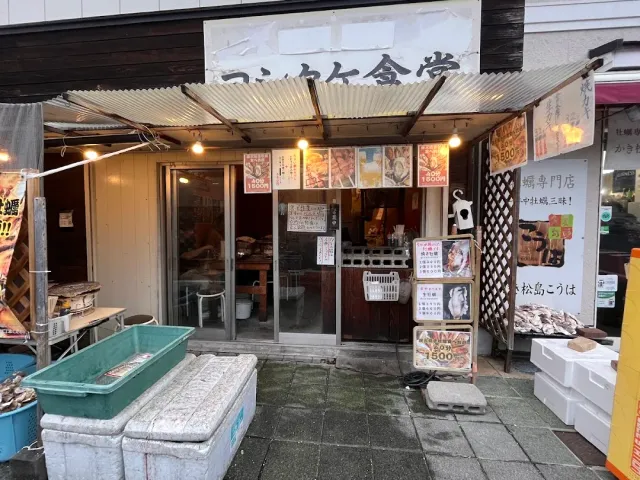 A modest frontage with a metal awning, photo posters of dishes and foam boxes on the pavement