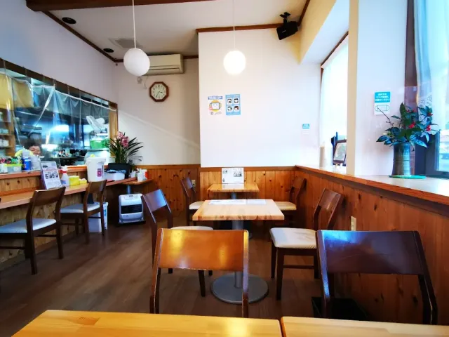 A small restaurant room with wooden tables, chairs and round lamps hanging from the ceiling