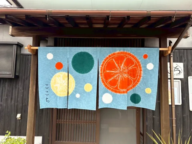 A light blue cloth curtain with colourful circles hanging above a wooden entrance