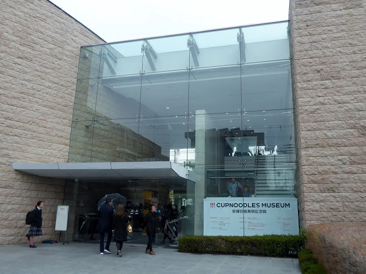 A glass and stone entrance to a modern building, with the museum sign to the right