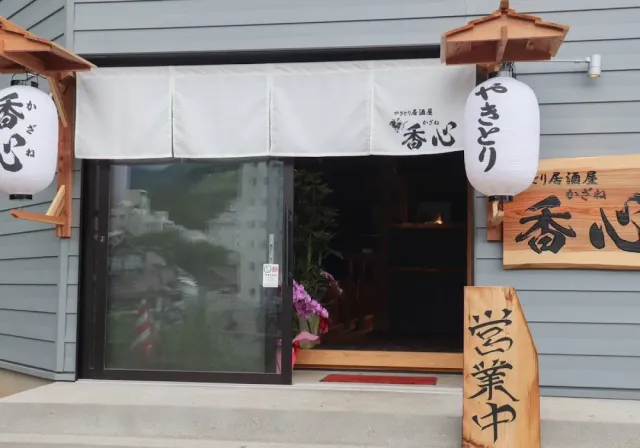 A shop entrance with a white cloth curtain, two paper lanterns and wooden signs on both sides