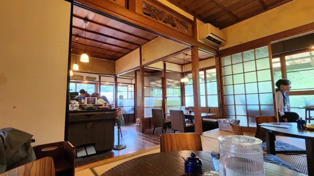 A Japanese style room with sliding doors, tables, seated guests and a jug on the table