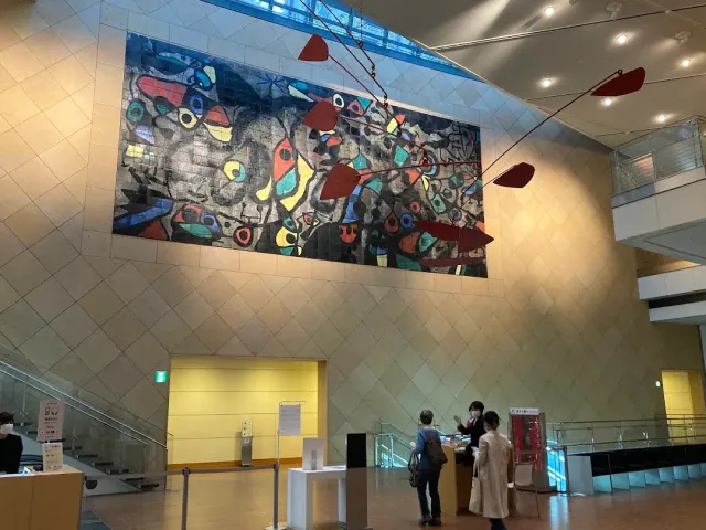 A high entrance hall with a colourful wall artwork and a red mobile hanging from the ceiling