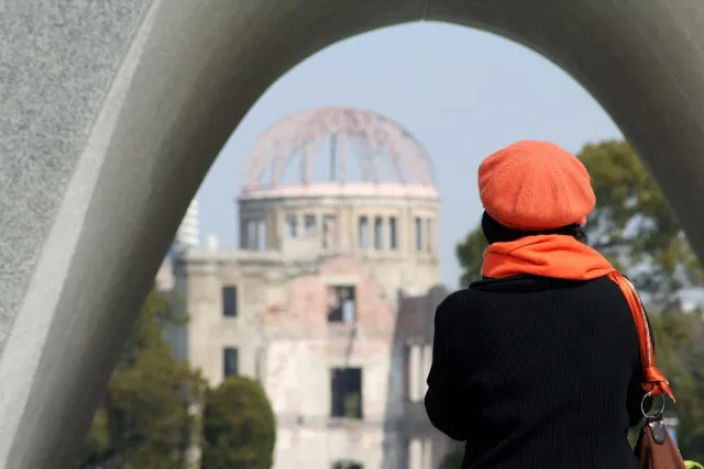 A visitor looking at a ruined domed shell through a concrete arch