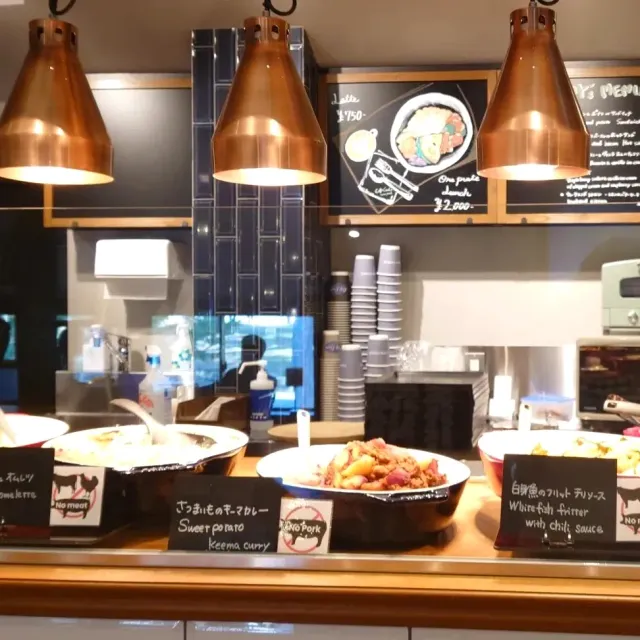 A serving counter with copper heat lamps, pots of dishes and chalkboards with the dish names