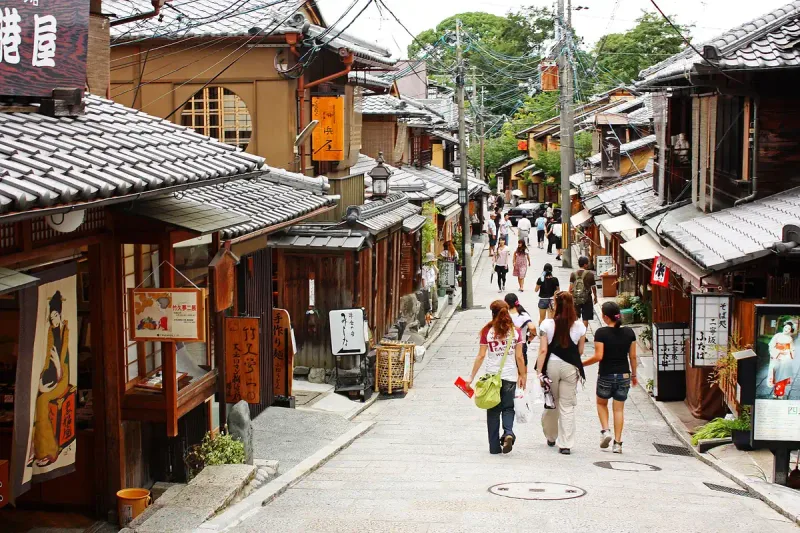 A narrow stone stepped lane with wooden shopfronts and visitors climbing it