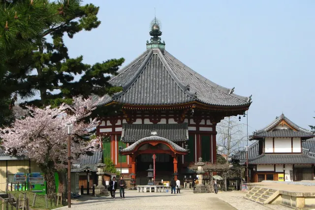 An octagonal temple hall with a tiered roof, among blossoming cherry trees