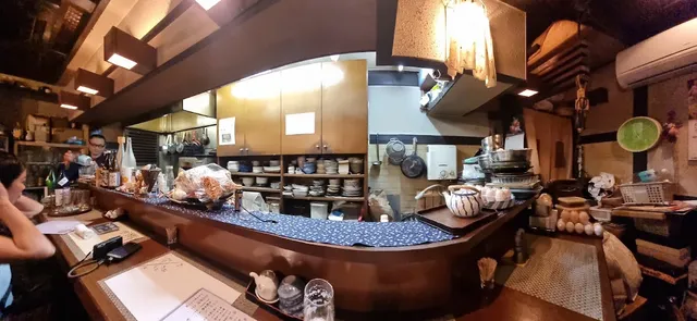 A curved counter with a blue cloth and a homely open kitchen behind it