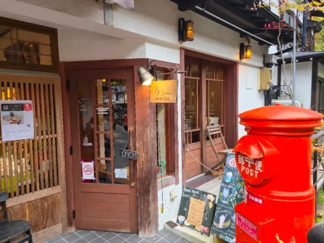 An entrance with an old wooden door, lamps on the wall, a chalkboard and a red mailbox