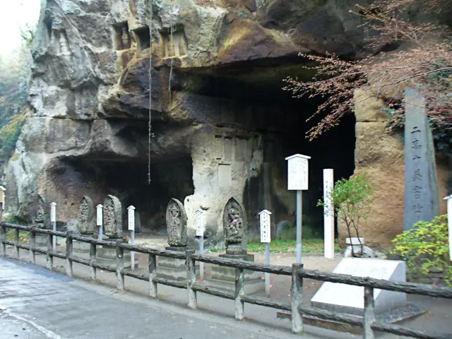 Caves carved into a rock face along a path, with blossoming trees