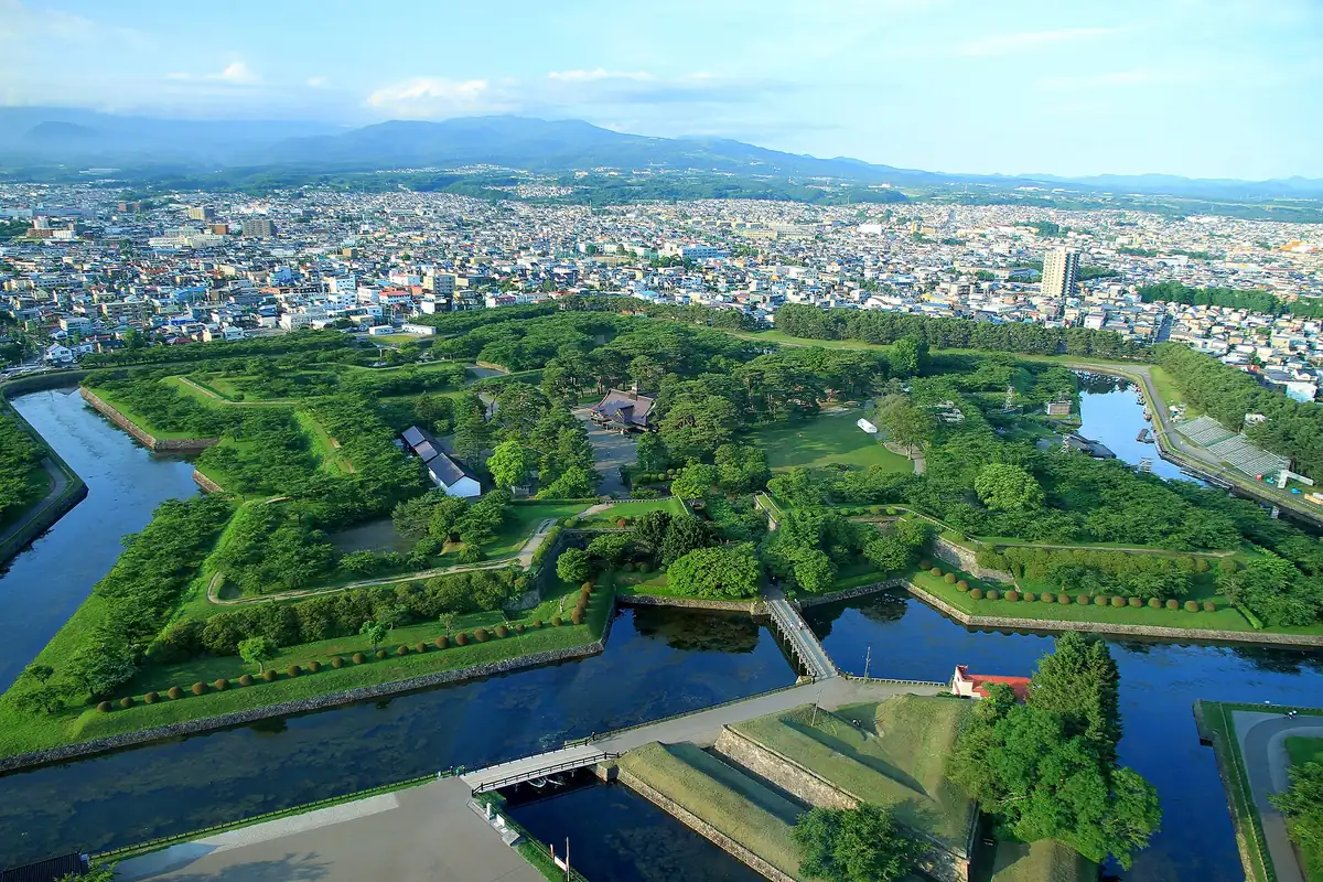 A view from above of a star shaped fort with water filled moats and green earth ramparts, with the city around it