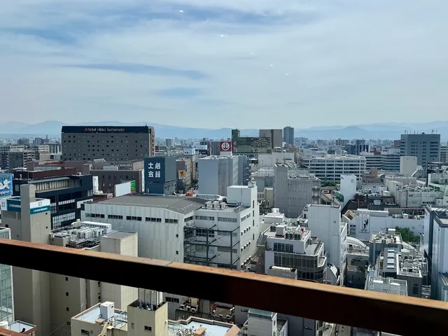 A city view from a high floor over rooftops and office buildings, with mountains on the horizon