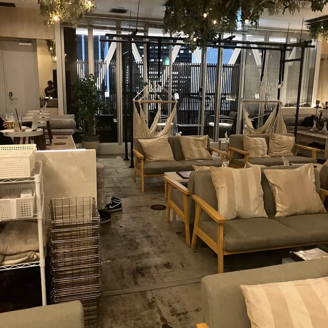 Wooden sofas with light cushions and hanging hammocks in front of tall windows